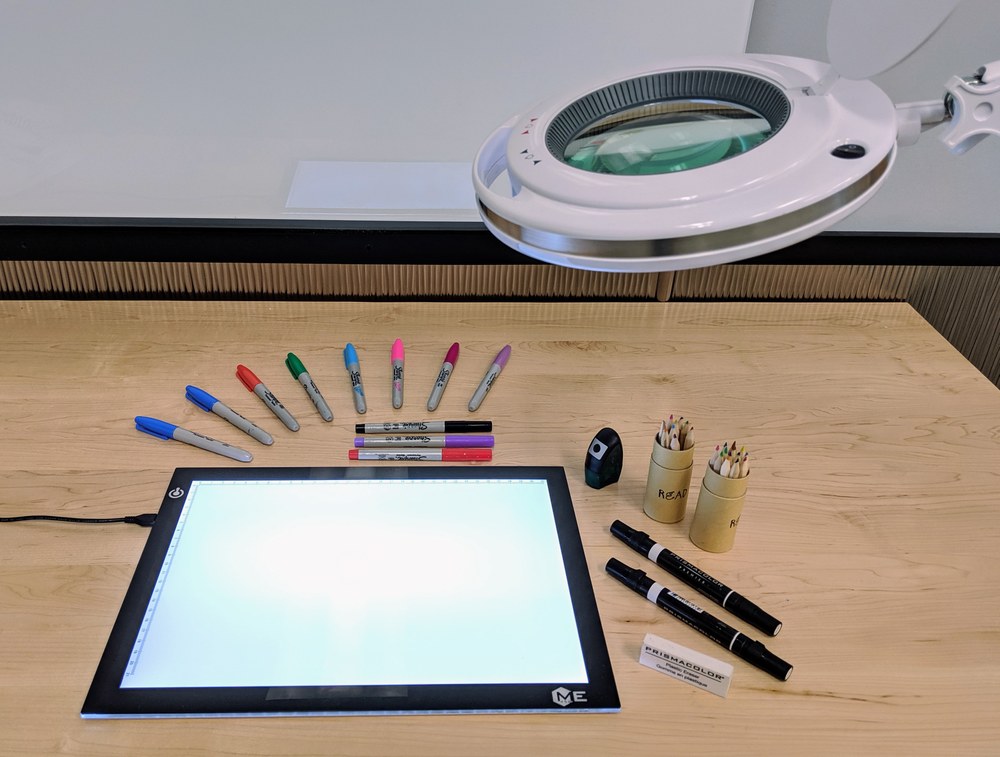 photo of drawing tools, including lighted tracing board, colored pencils, and markers